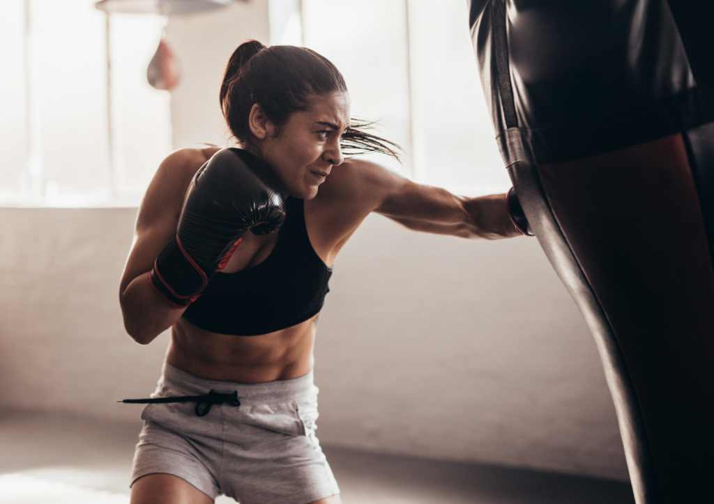 Mujer en el dojo de José María practicando crochés con saco de boxeo 
